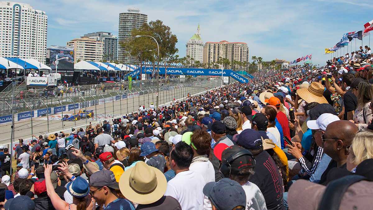 crowd watching race car on track with view of buildings in distance during day at Grand Prix of Long Beach in Los Angeles, California, USA