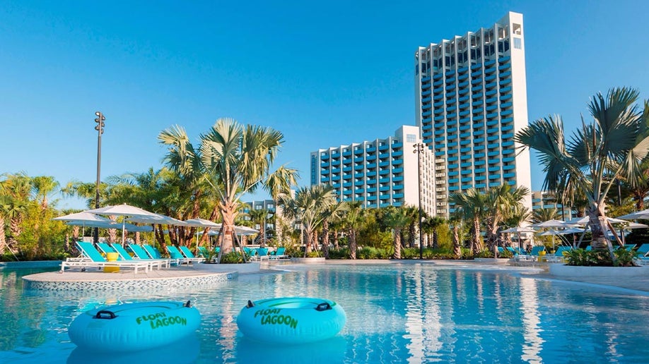 pool and pool rings with lounge chairs and palm trees with view of exterior of Hilton Orlando Buena Vista Palace Disney Springs Area in background in Orlando, Florida, USA
