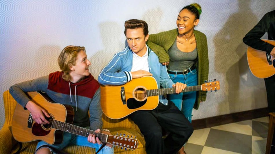 a photo of a men holding their guitar while the girl is talking with the other man
