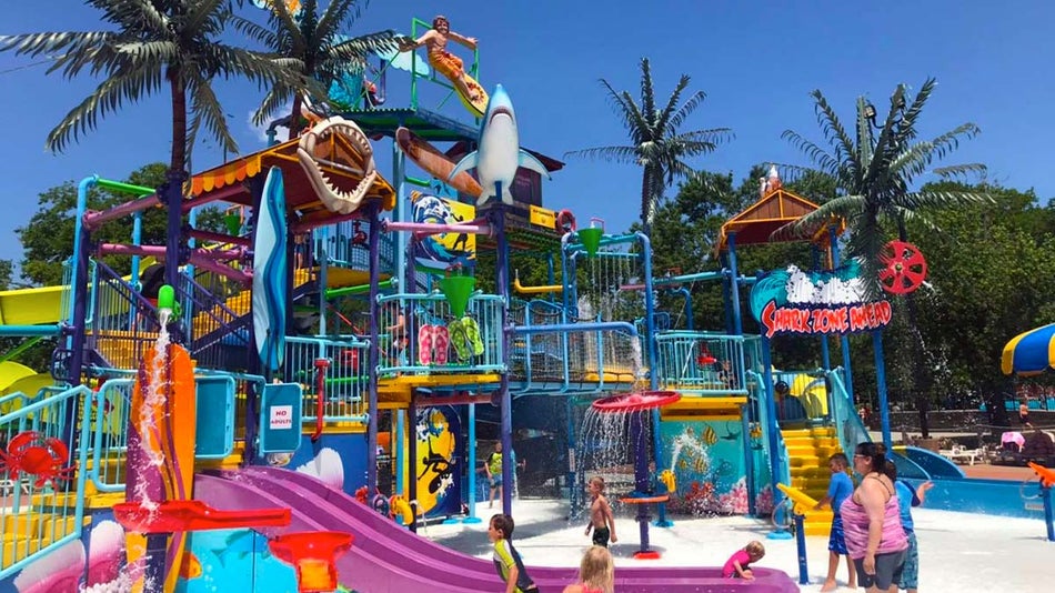 a front view of water slides in the pool, and are children enjoying it.