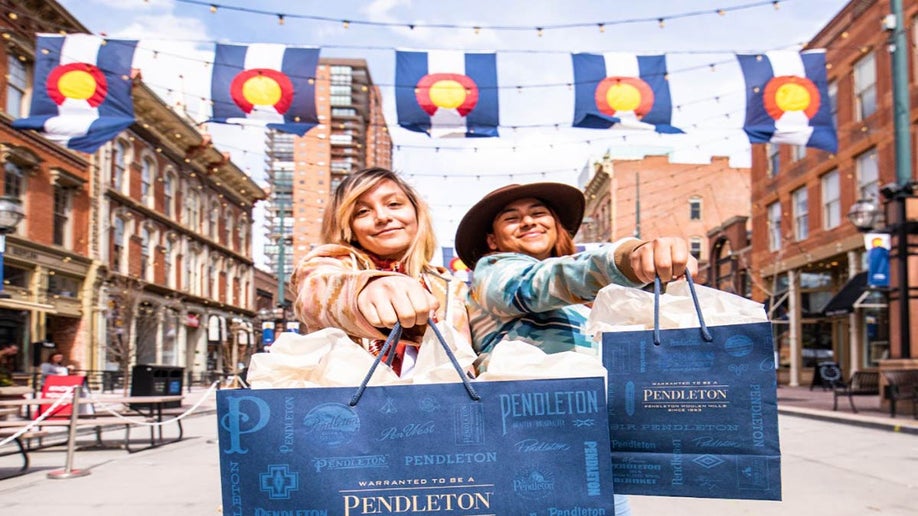 close up of two women holding out shopping bags at Larimer Square in Denver, Colorado, USA