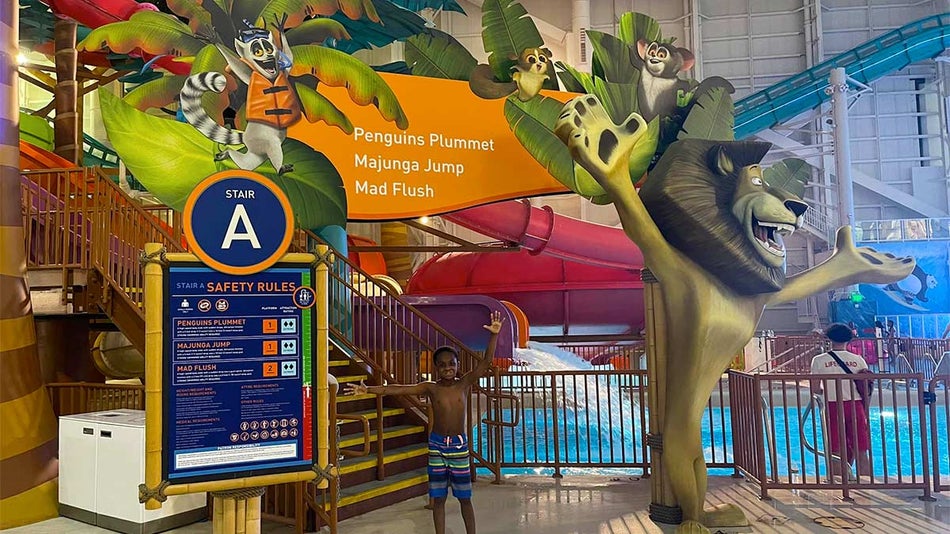 child posing under entrance to Mad Flush slide at DreamWorks Water Park in New Jersey, USA