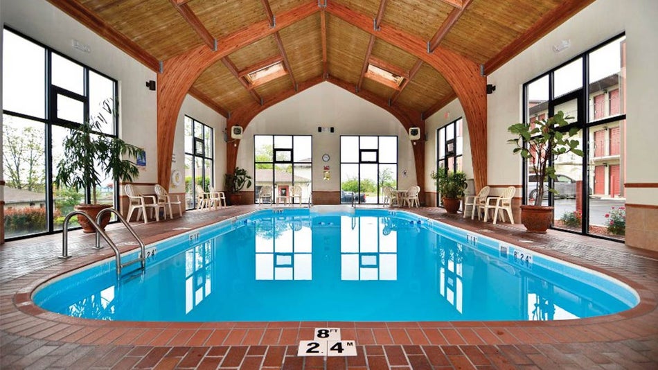 blue indoor pool in room with white walls and wooden roof at Quality Inn West in Branson, Missouri, USA