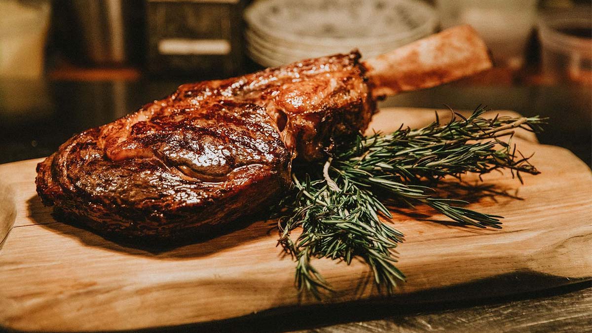 close up of meat with rosemary sprig on side on wooden board at Ravenous Pig in Orlando, Florida, USA