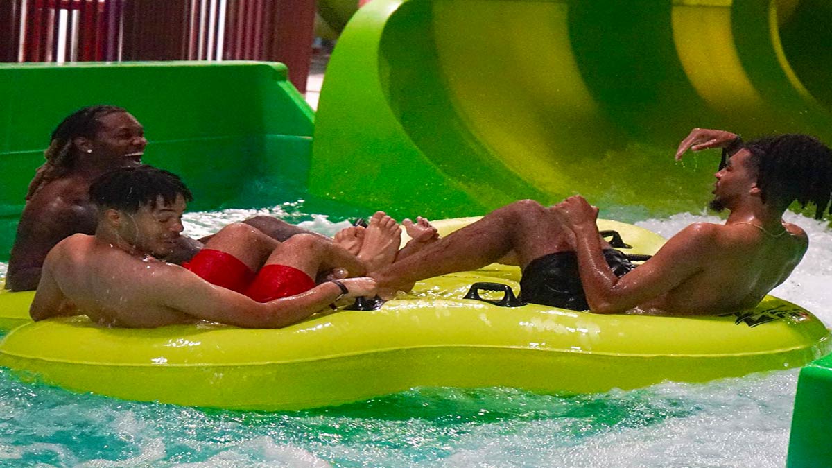 friends on green float aboard Shrek's Sinkhole ride at DreamWorks Water Park in New Jersey, USA