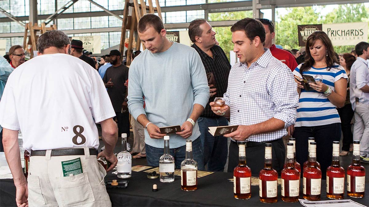 people holding passbooks sampling drinks at booth at Tennessee Whiskey Festival in Gatlinburg, Tennessee, USA