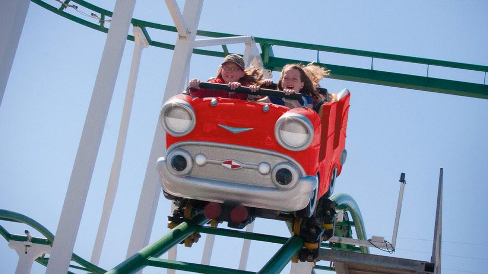A girl enjoys riding a moving roller coaster.