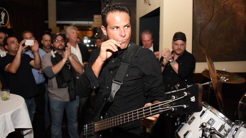 musician with bass guitar performing with crowd in background at Vines Grille and Wine Bar in Orlando, Florida, USA