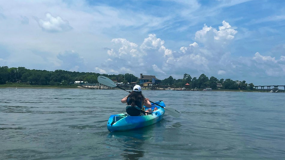 Woman wearing white hat kayaking in water during day in Hilton Head, South Carolina, USA
