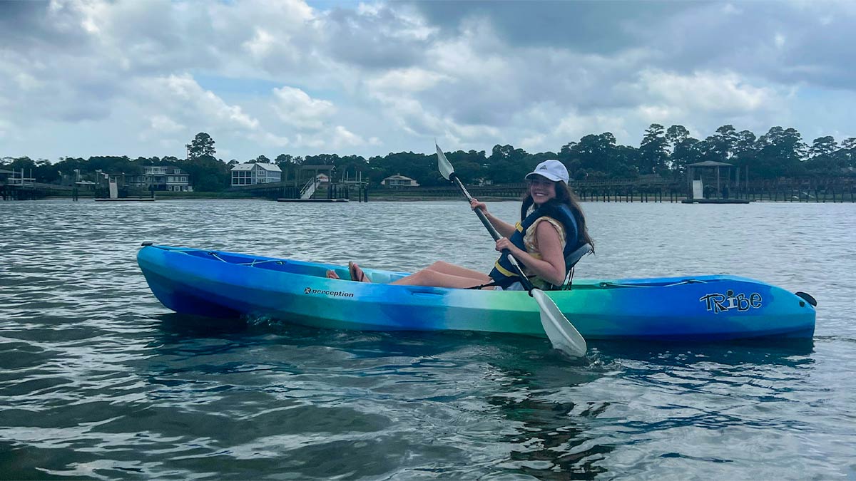 woman wearing white hat kayaking with view of houses and trees in background during day in Hilton Head, South Carolina, USA