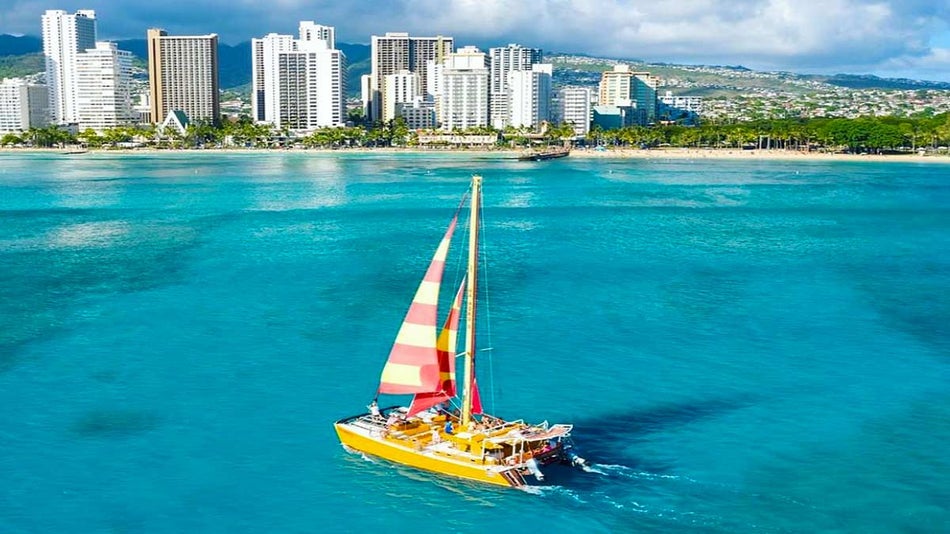 aerial of yellow boat on water with view of shore and buildings during day for Adventure Sail Waikiki in Hawaii, USA