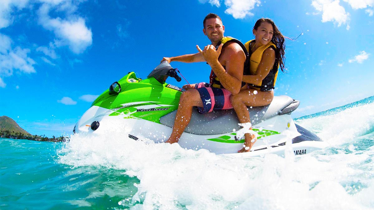 couple on Jet Ski with mountain in distance on sunny day in Oahu, Hawaii, USA