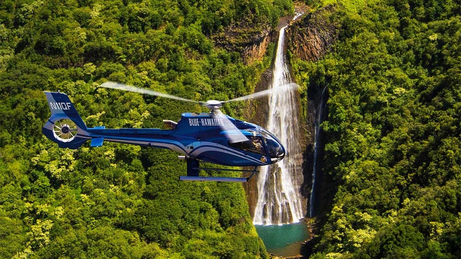 helicopter flying over landscape with trees and waterfall at Kauai Eco Adventure Helicopter Tour in Kauai, Hawaii, USA