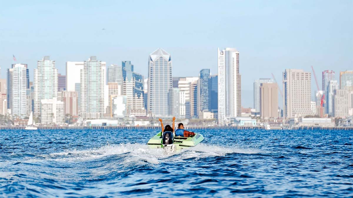 couple on green speed boat during day with view of buildings in background for San Diego Speed Boat Adventures in San Diego, California, USA