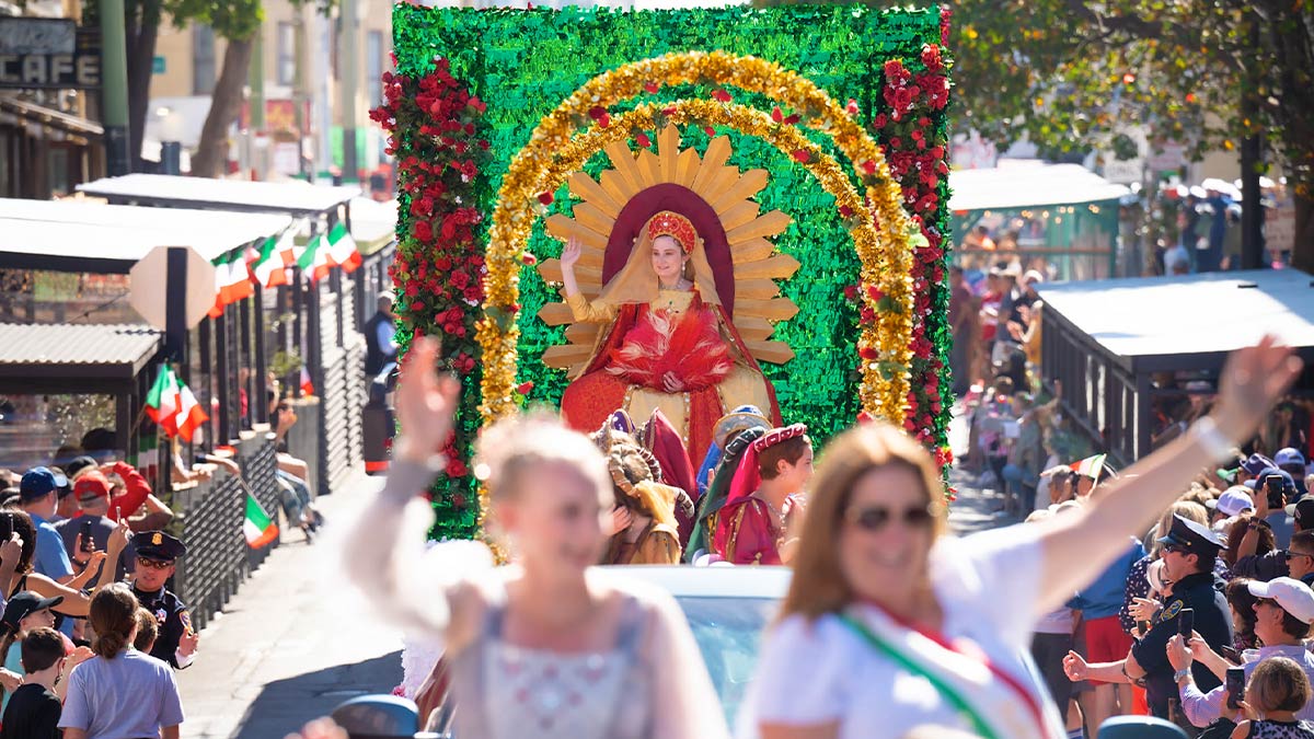 women in festive clothing on float with crowd watching on the sides at San Francisco Italian Heritage Parade in San Francisco, California, USA