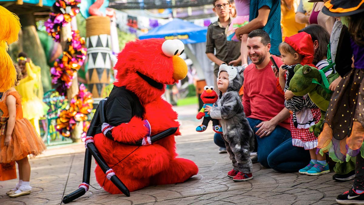 Elmo mascot interacting with children in costumes and parents at Sesame Street Safari of Fun Halloween Kids Weekends Busch Gardens in Tampa, Florida, USA