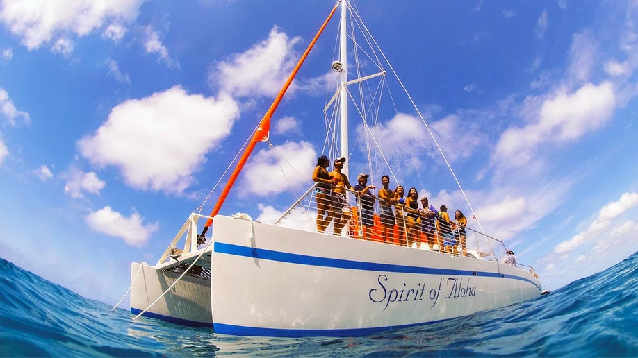 people aboard Spirit of Aloha Catamaran during day with blue sky and clouds in Oahu, Hawaii, USA