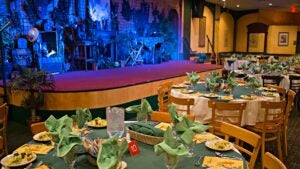 Food is served at various dining tables with a bright green theme next to the stage.