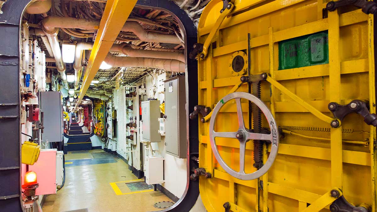 Internal shot down a hallway of the USS Missouri Battleship, yellow walls and yellow door with a wheel 