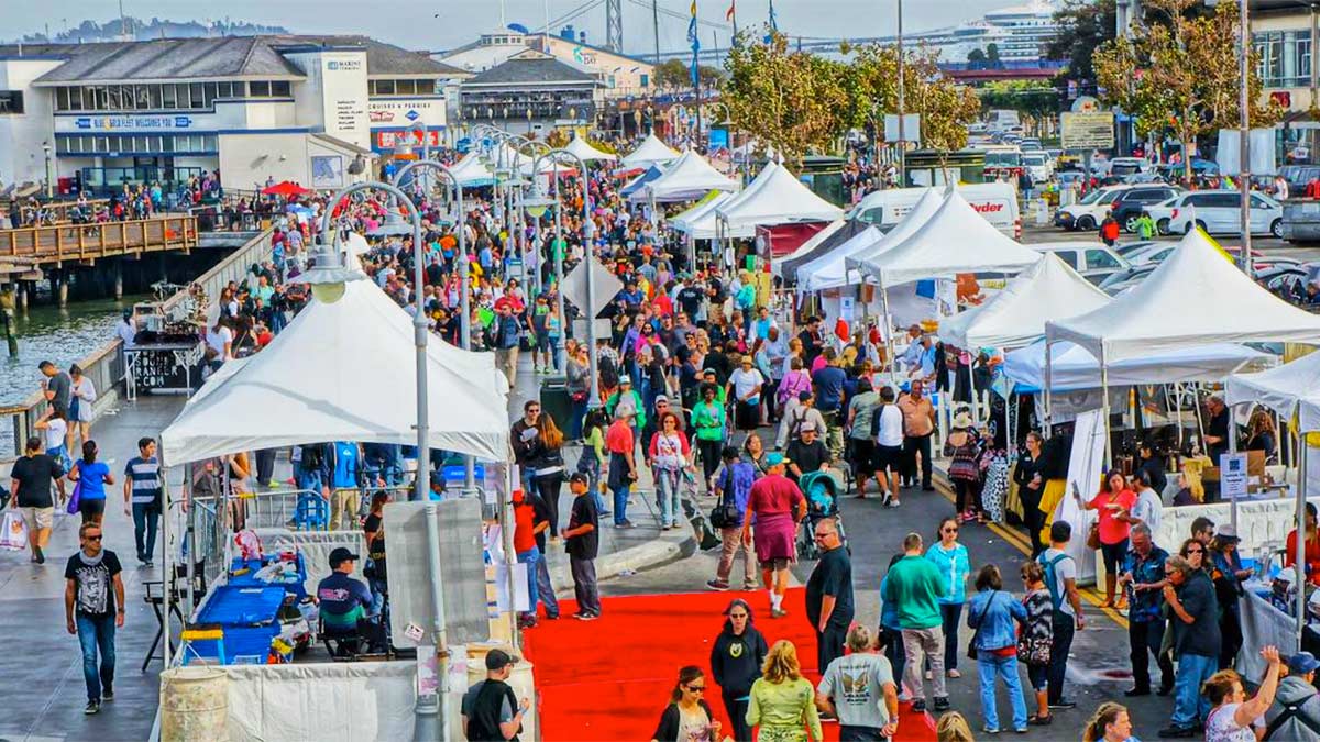 crowd walking by booths during day at Wharf Fest in San Francisco, California, USA