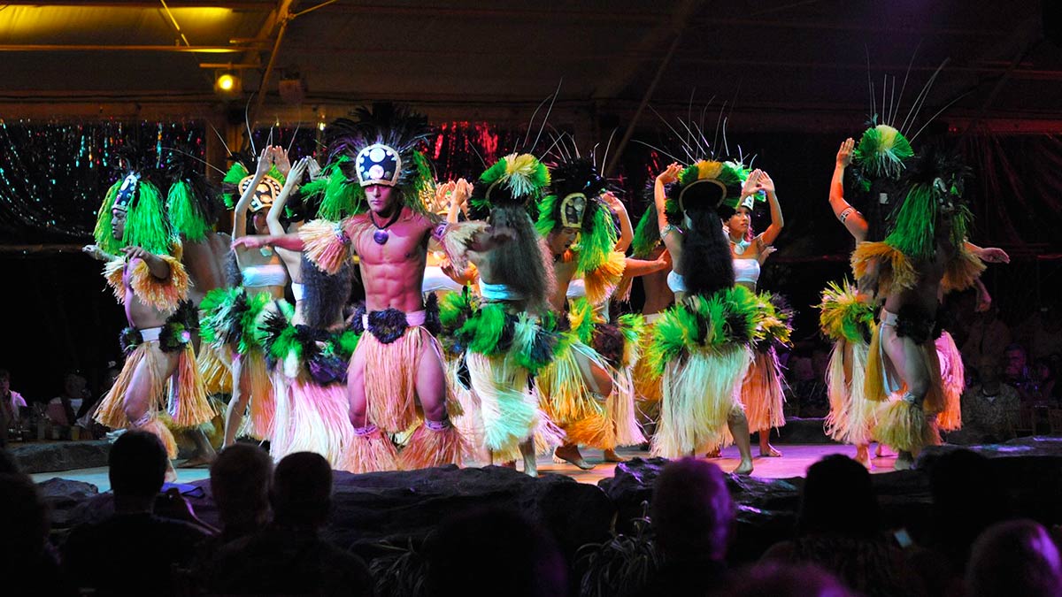 dancers on stage in traditional wear with crowd watching in bottom at Luau Kalamaku in Kauai, Hawaii, USA
