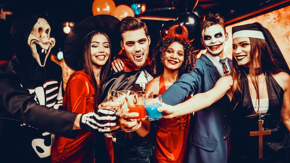 group of friends in halloween costumes toasting drinks at A Nightmare on Church Street event in Orlando, Florida, USA