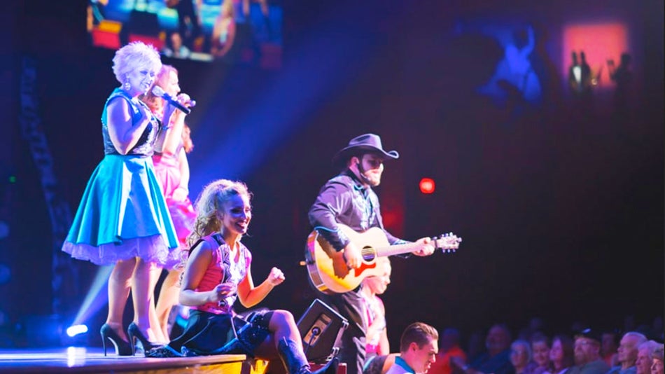 singers holding microphone and musician with guitar performing on stage in front of crowd at Country Tonite Show in Pigeon Forge, Tennessee, USA