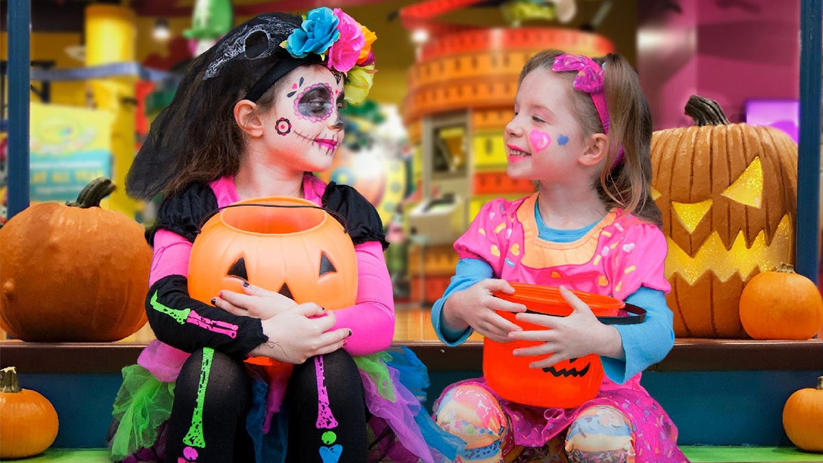 two girls in halloween costumes holding pumpkin buckets at Crayola Experience Orlando Screamin Green Hauntoween event in Orlando, Florida, USA