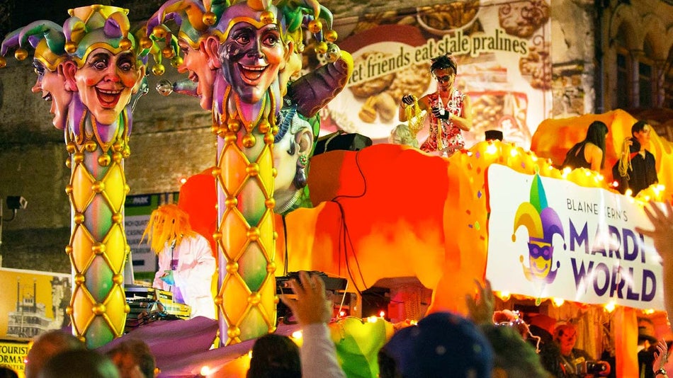 people in costume on colorful float decorated with jester heads with crowd gathered at the side at night at Krewe of Boo Halloween Parade in New Orleans, Louisiana, USA