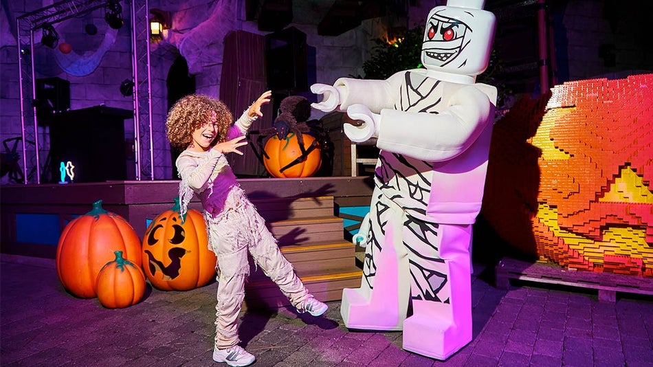 A photo of a kid in Halloween costume enjoying the place with a monster lego man