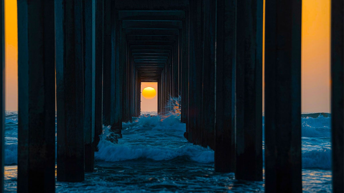 sunset at Scripps Pier with waves in San Diego, California, USA