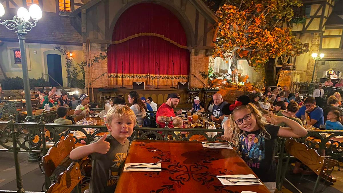 close up of kids seated at table in Biergarten (Germany) with diners in the background in front of stage with closed red curtains at Epcot in Orlando, Florida, USA