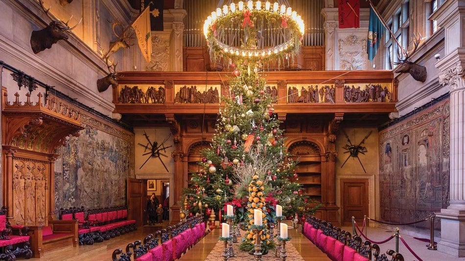 wideshot of dining area with large table and chairs, christmas trees, and chandelier and wood carvings on walls at Biltmore House in Asheville, North Carolina, USA