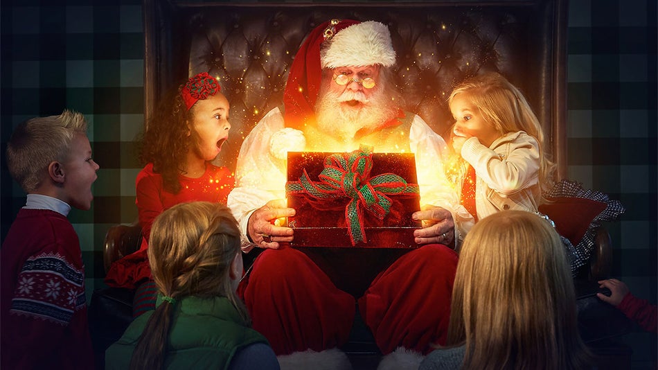 santa opening gift while seated with children at Christmas Place in Pigeon Forge, Tennessee, USA