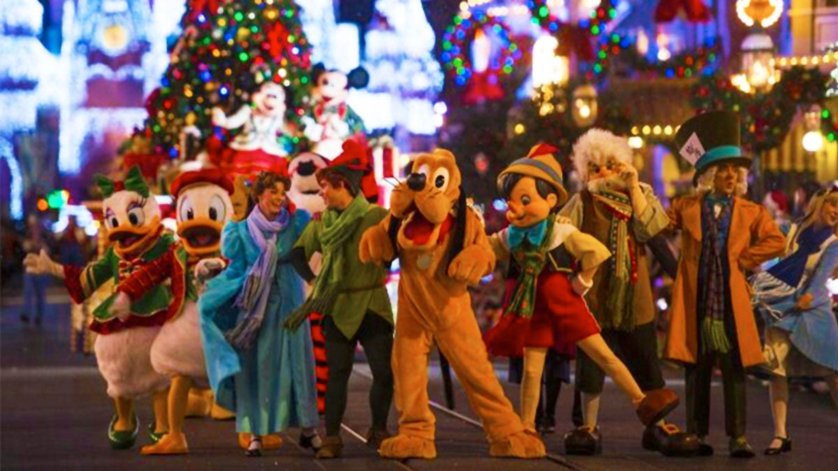 Disney character actors arm in arm with micky and minnie mascots on float with christmas tree in background at Mickeys Very Merry Christmas Party in Orlando, Florida, USA