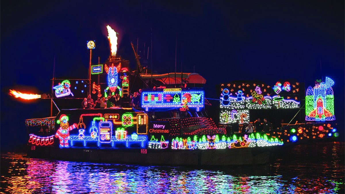 boat on water decorated with colorful lights at night in Newport Beach Christmas Boat Parade in Los Angeles, California, USA