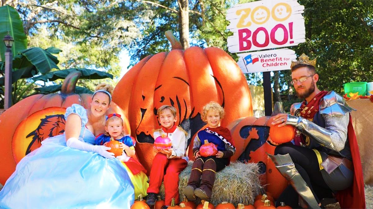 family in costume posing with large pumpkins during day at San Antonio Zoo Zoo Boo in San Antonio, Texas, USA