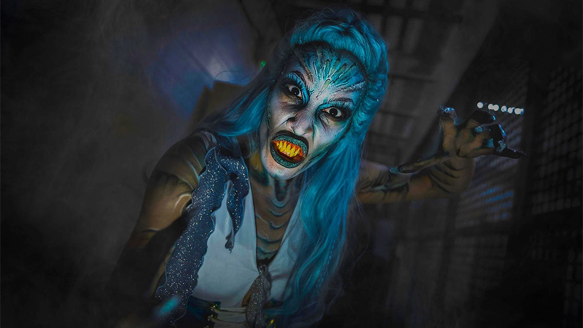 performer in costume with blue hair and theatrical make up posing for photo at SeaWorld Orlando Howl-O-Scream in Orlando, Florida, USA
