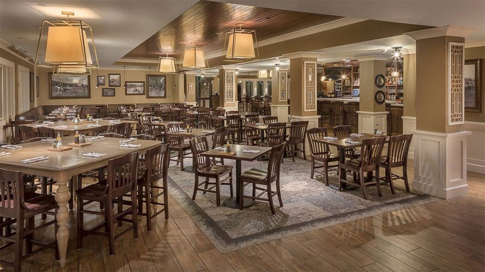 interior of The Village Social and Bistro with set wooden dining tables and chairs and wooden floors with rug at Biltmore in Asheville, North Carolina, USA