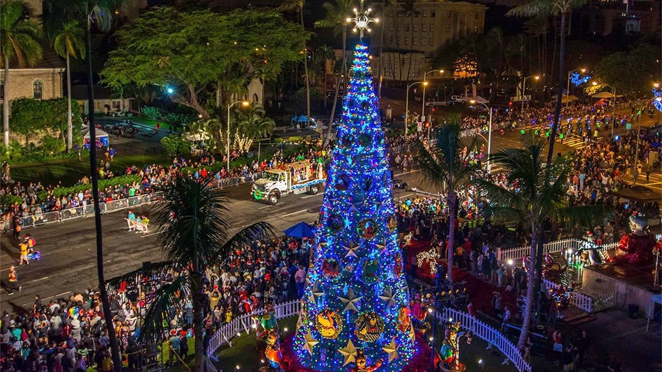 A crowd of people gathered around a large blue Christmas Tree at night during Honolulu City Lights on Oahu, Hawaii, USA.
