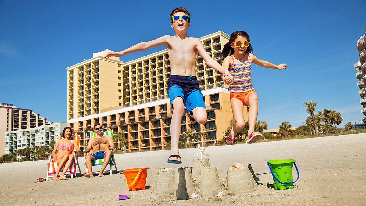 Kids Jumping Over Sandcastle on Myrtle Beach