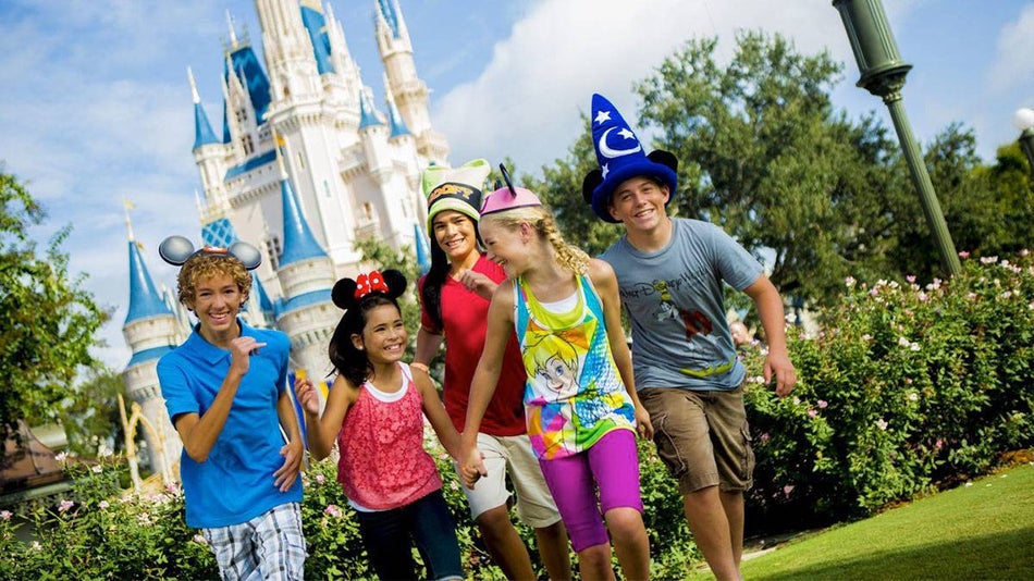 group of excited kids running in front of cinderella castle at walt disney world orlando, florida