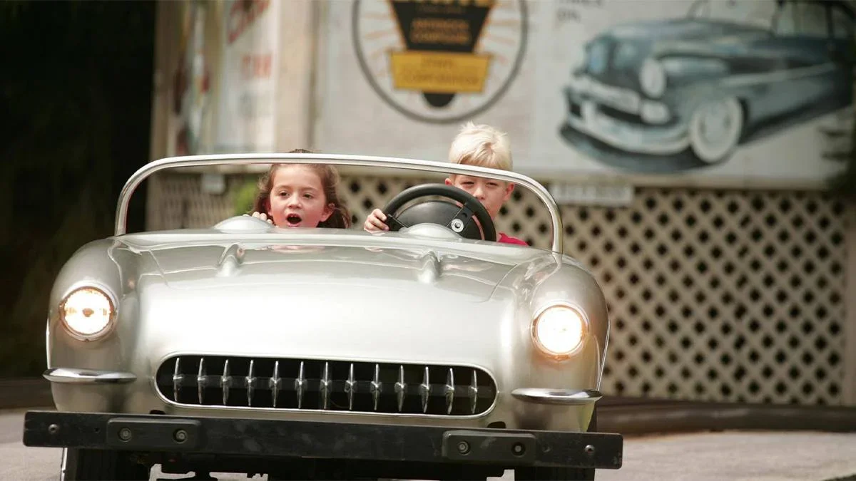 Close up of two kids in a silver car on the Rocking' Roadway at Dollywood on a sunny day