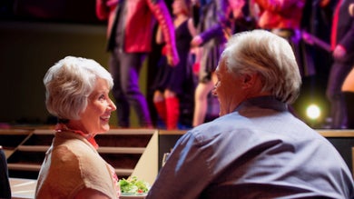 senior adults sitting at a dinner table with performers in the background on the show boat branson belle