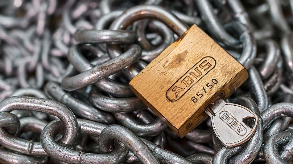 Close up of lock with key on pile of chains