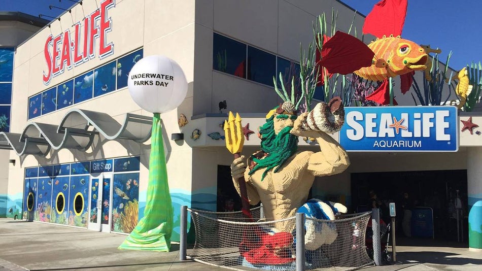 Entrance to the Sea Life Aquarium decorated with LEGO statues of Poseidon and an orange fish on a sunny day in San Diego, California, USA