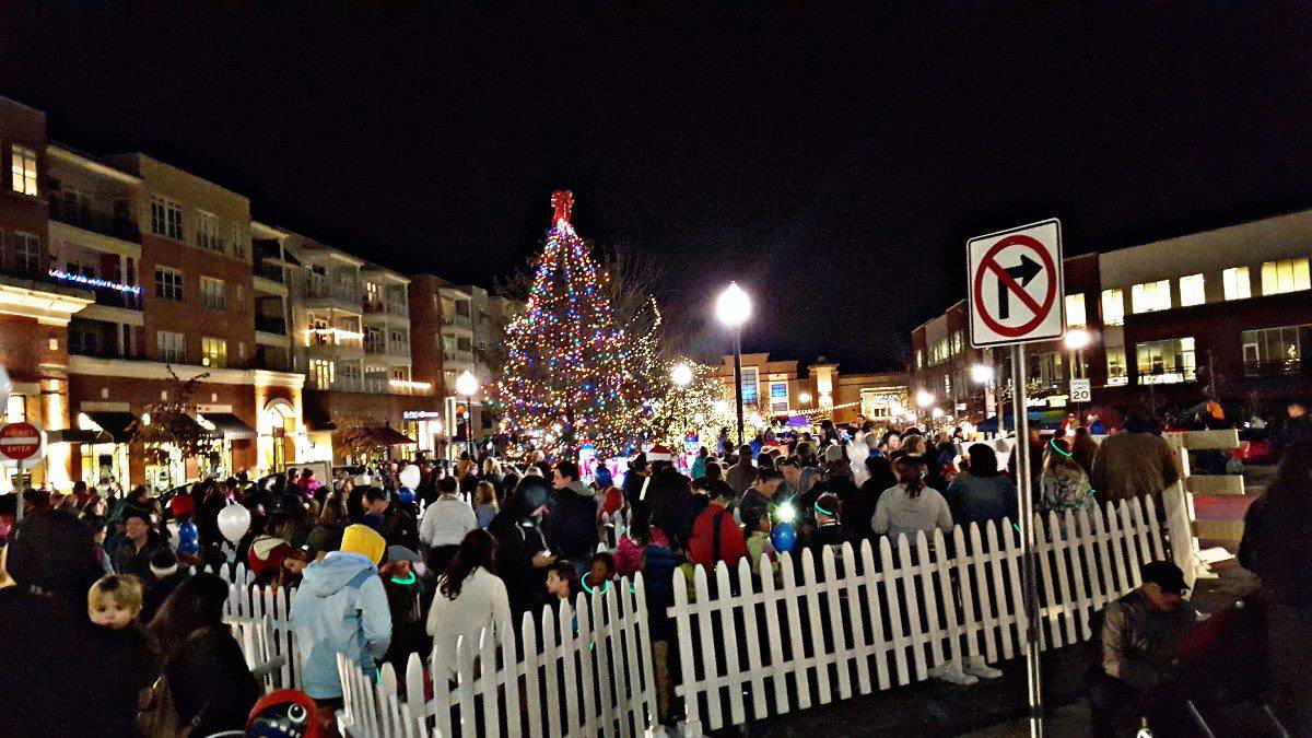 Wide shot of a large crowd of people surrounding a giant Christmas Tree at Biltmore Park Town Square in Asheville, North Carolina, USA