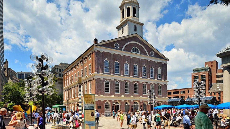 Exterior of Faneuil Hall with crowd of people outside and street lamps on a sunny day in Boston, Massachusetts, USA