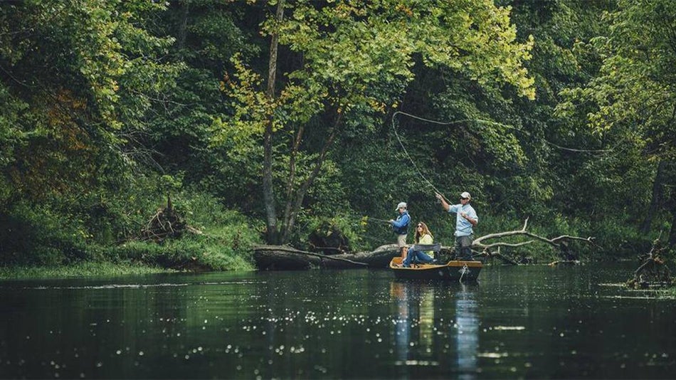 Three people in the boat fishing near some trees on Lake Taneycomo in Branson, Missouri, USA
