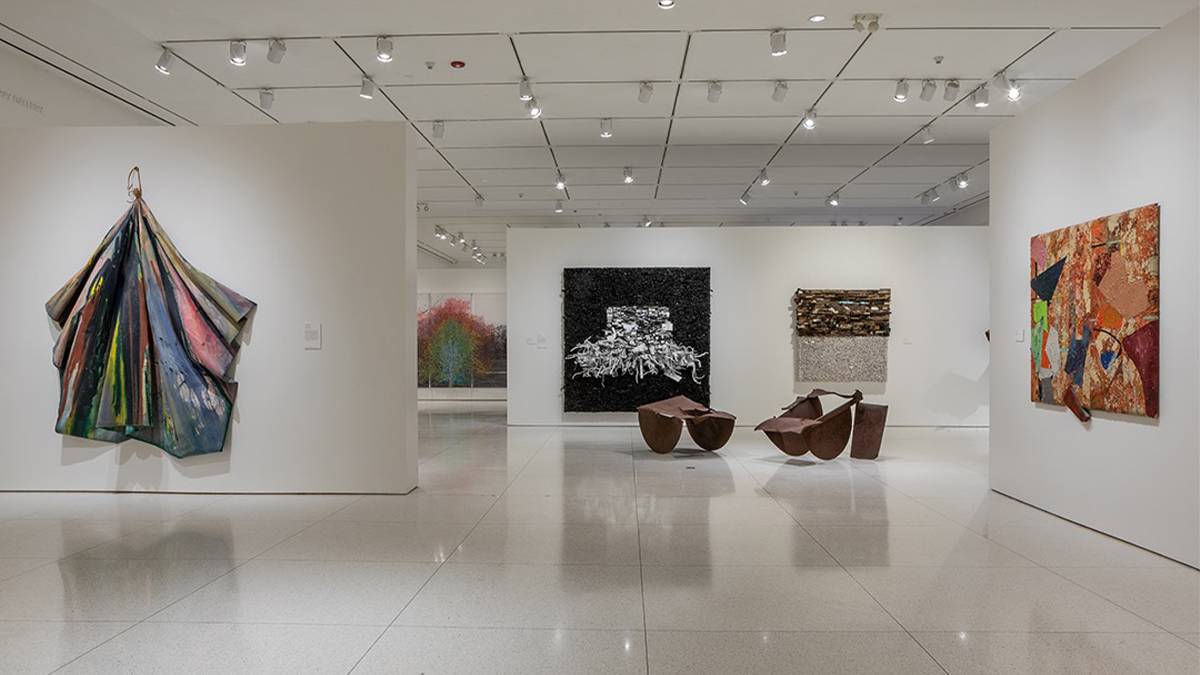 Wide shot of a room with white walls and floors and with different art pieces on the walls and a metal sculpture on the floor at Smart Museum of Art in Chicago, Illinois, USA